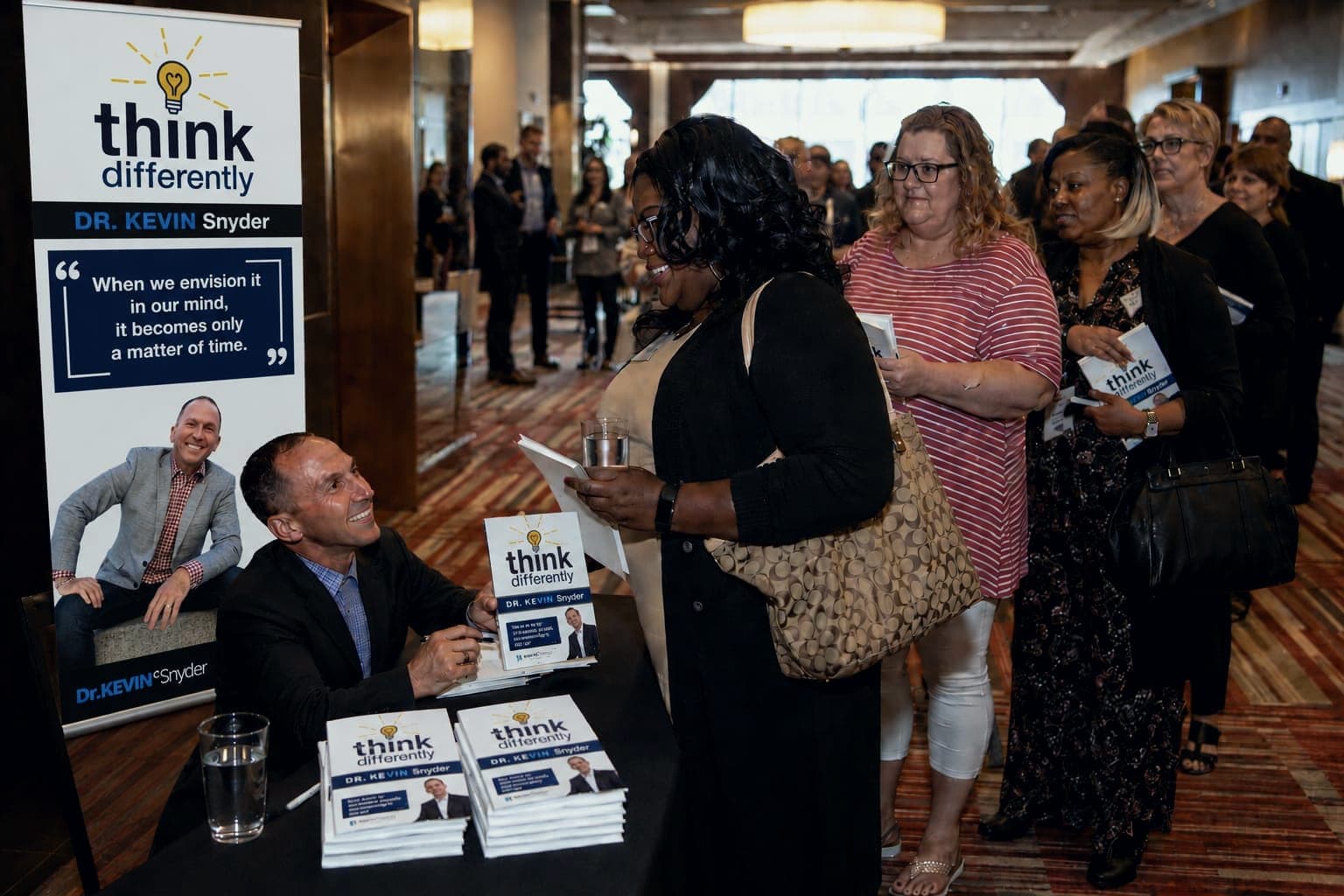 Kevin signing copies of his book Think Differently for a line of readers