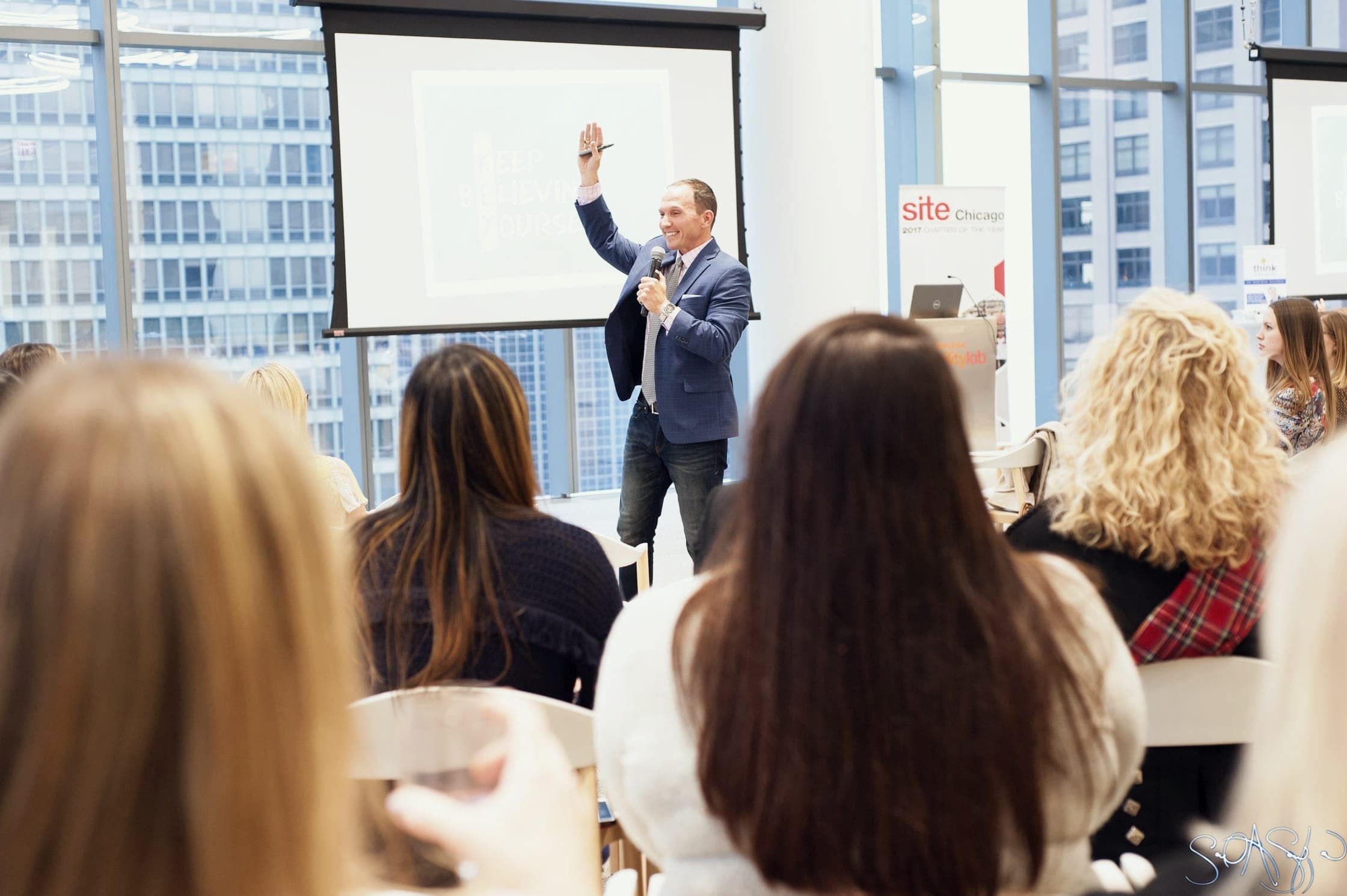 Kevin leading a workshop in a bright city meeting room, hand raised